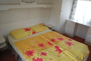 Una cama con una manta amarilla con flores. en ubytování na kopečku, en Velké Svatoňovice