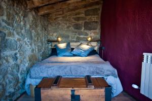 a bedroom with a bed in a stone wall at Can Poca Roba in Sant Pere de Torelló