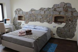 a bedroom with a bed with a stone wall at b&b il Portico Orgosolo in Orgosolo