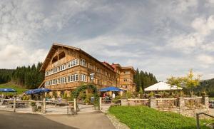 un grand bâtiment avec des personnes assises à l'extérieur dans l'établissement Auenhütte, à Hirschegg