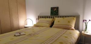 una camera da letto con letto, lenzuola e cuscini gialli di Genius Guest Unique Banovci Apartment a Banovci