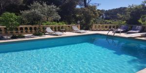 a blue swimming pool with chairs and a fence at Le Domaine d'Alèzen in Grans