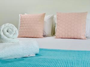 a bed with pink pillows and towels on it at AIRLIE BEACH Delight. Hop, skip jump to everything in Cannonvale