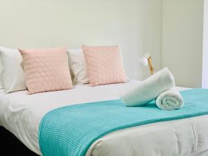 a white bed with pink and blue sheets and pillows at AIRLIE BEACH Delight. Hop, skip jump to everything in Cannonvale