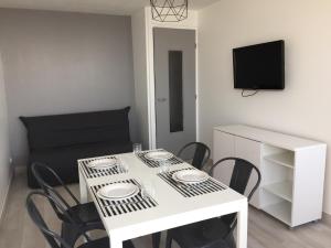 een witte tafel met stoelen en een televisie in een kamer bij Entre mer et falaises in Le Tréport