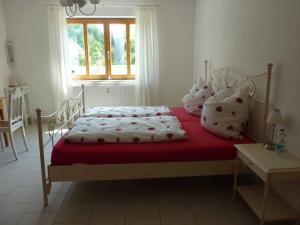 Schlafzimmer mit einem Bett mit roter und weißer Bettwäsche und Kissen in der Unterkunft Ferienwohnung Fantaisie in Eckersdorf