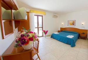 1 dormitorio con 1 cama y flores en una mesa en Hotel Orchidea, en Peschici