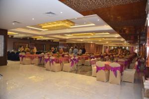a banquet hall with tables and chairs with purple bows at HOTEL JD HEAVENS in Jhajjar