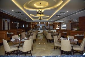 a restaurant with wooden tables and chairs and a chandelier at HOTEL JD HEAVENS in Jhajjar