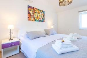 two beds in a white bedroom with a painting on the wall at Apartment Laura in Dubrovnik