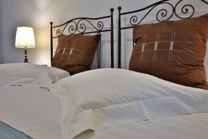 un letto con lenzuola e cuscini bianchi e una lampada di Ostria Studios ad Adámas