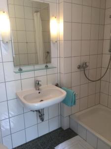 La salle de bains blanche est pourvue d'un lavabo et d'une douche. dans l'établissement Gästeapartment Kübel, à Uedem