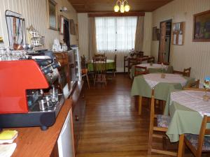 a restaurant with two tables and a kitchen with a coffee maker at Hostal Opapa Juan in Puerto Varas