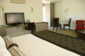 Habitación de hotel con cama, TV y mesa. en Springs Mittagong en Mittagong