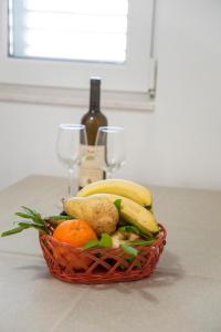 a basket of fruit and vegetables with a bottle of wine at Apartments Mako in Herceg-Novi