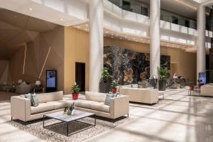 Cristal Amaken Hotel Riyadh في الرياض: لوبي فيه كنب وطاولات في مبنى