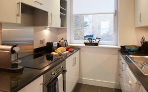 a kitchen with white cabinets and black counter tops at Cheval Harrington Court at South Kensington in London