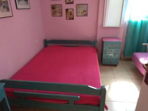 Un dormitorio con una cama roja en una habitación rosa en Anthi Apartment, en Palaión Tsiflíkion
