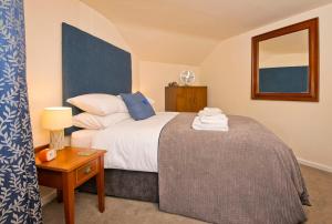 ein Schlafzimmer mit einem Bett und einem Tisch mit einer Lampe in der Unterkunft Cottage Retreat near Peak District and Chatsworth House in Matlock