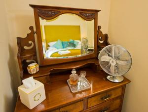 een slaapkamer met een spiegel en een ventilator op een dressoir bij Cottage Retreat near Peak District and Chatsworth House in Matlock