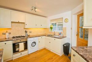 a kitchen with white cabinets and a washing machine at Cottage Retreat near Peak District and Chatsworth House in Matlock