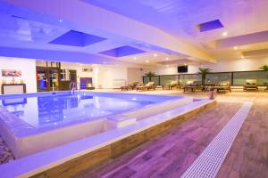 a large swimming pool in a large room with tables and chairs at Zenia Hotel & Spa in Cambrai