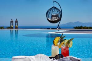 a table with two cocktails next to a swimming pool at Golden East in Imerovigli