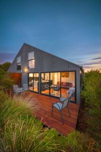 a house on a wooden deck with a chair at Southern Ocean Villas in Port Campbell