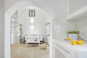 Una sala de estar blanca con un sofá y una mesa. en Golden East, en Imerovigli