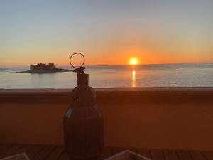 una botella en una cornisa con una puesta de sol en el fondo en La casa dell'Alba, en Marzamemi