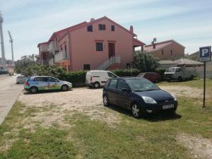 un grupo de coches estacionados frente a una casa rosa en Apartments Marija, en Zadar