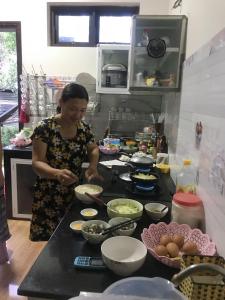 a woman standing in a kitchen preparing food at Countryside Garden Homestay in Hoi An