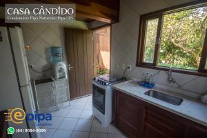 cocina con fogones, fregadero y ventana en Pipa Casa Candido (Condominio Pipa Natureza), en Pipa