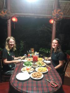 two women sitting at a table with food at Countryside Garden Homestay in Hoi An