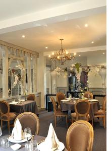 a dining room with tables and chairs and a chandelier at Logis Hôtels Restaurant Les 3 Rois in Issoudun