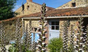 una casa de ladrillo con una puerta de garaje blanca y algunas plantas en Chambres d'hôtes les Hautes Papinières en Saint-Prouant