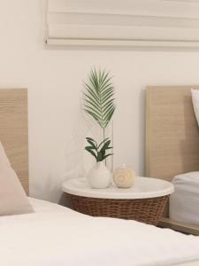 un vase blanc avec une plante sur une table à côté d'un lit dans l'établissement Neat House, à Séoul