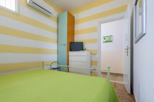 a bedroom with a green bed and a television at Casa La Formica in Noto