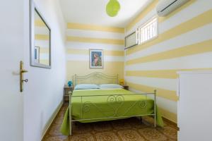 a bedroom with a green bed in a room with striped walls at Casa La Formica in Noto