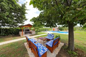 a group of benches sitting under a tree next to a pool at EasyLiving House near Zadar in Posedarje