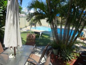 a table with a umbrella next to a swimming pool at Shell Motel (Pearly Shell Motel) in Bowen