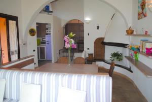 Un comedor con una mesa con un jarrón de flores encima. en VILLA STELLA fronte mare Porto Frailis, en Àrbatax