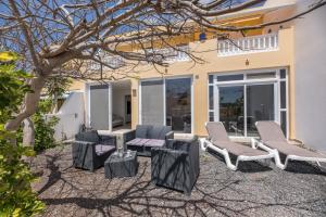 un patio con sillas, una mesa y un árbol en ampio luminoso 3 camere 3 bagni giardino quiete Wi-Fi, en Costa Calma