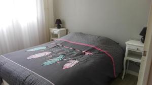 a bed with a gray comforter with feathers on it at L'appart de lônes in Hauteville-Lompnes +36 photos