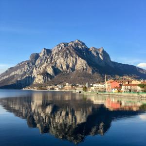 un reflejo de montaña en un cuerpo de agua con una ciudad en Villa Maggie on Lake Como, en Malgrate