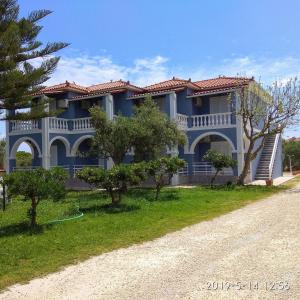 una casa azul con árboles al lado de una carretera en Stelios Studios, en Tragaki