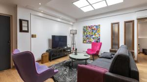 uma sala de estar com um sofá e cadeiras e uma televisão em 3-bedroom apartment Quai des Grands Augustins em Paris