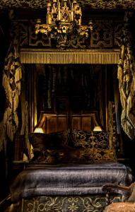 a black and gold bed with a chandelier above it at The Witchery by the Castle in Edinburgh