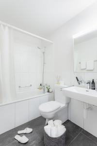 La salle de bains blanche est pourvue d'un lavabo et de toilettes. dans l'établissement Swiss Star Wiedikon - Self Check-In, à Zurich