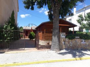 a wooden building with a gate next to a tree at CABAÑAS DE MADERA LA FLORIDA in Arroyo Frio